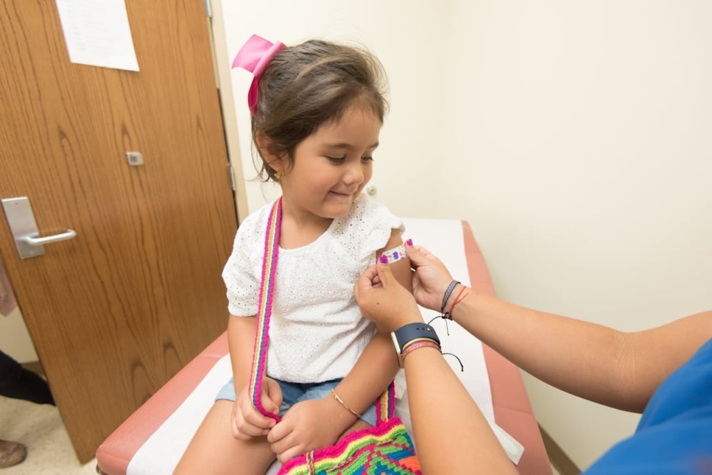 Nurse putting a band aid on a young child in a medical practice