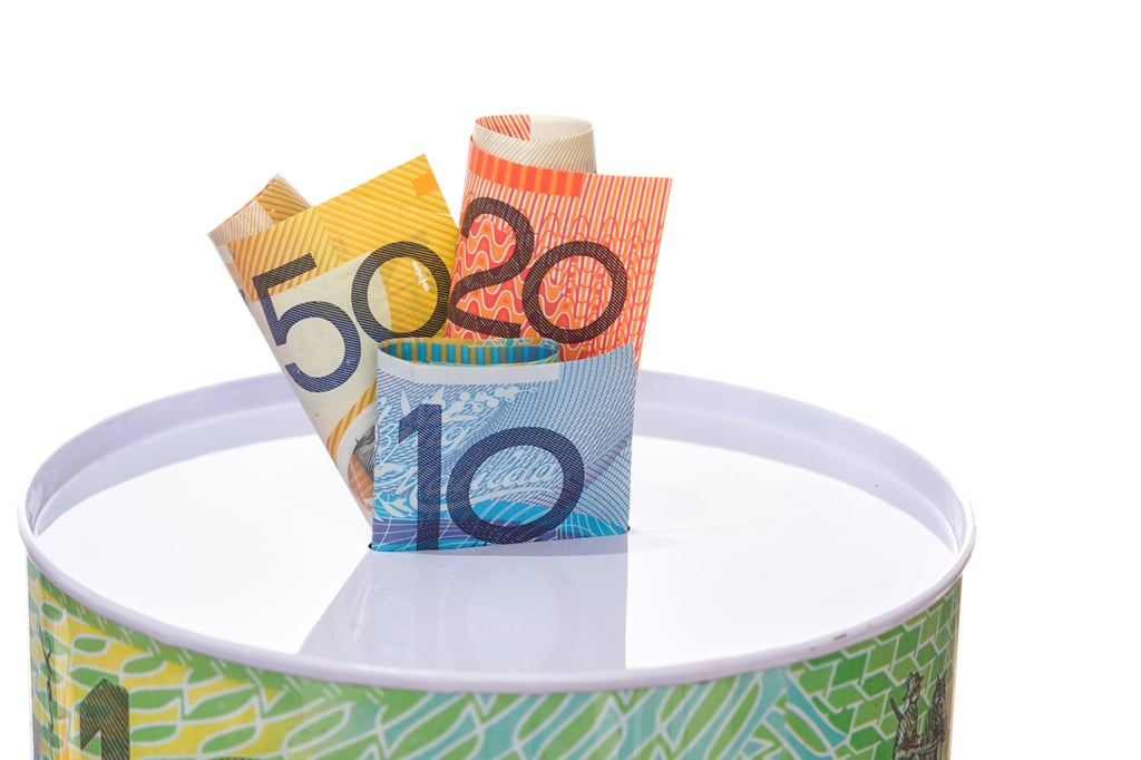 Australian notes sticking out of a savings tin