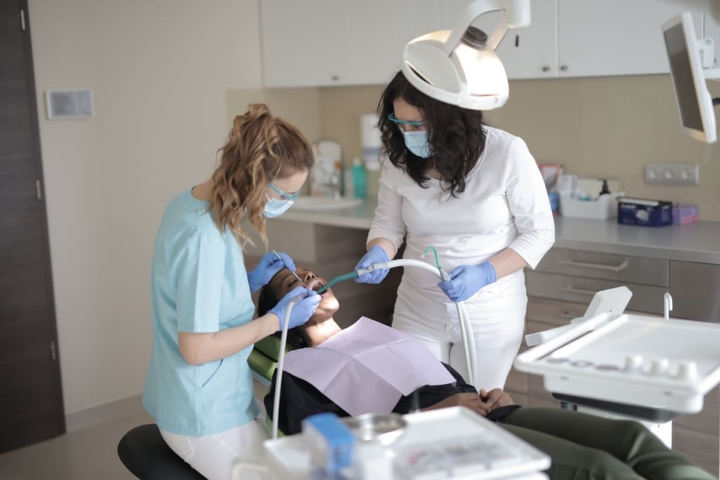 Dentist and hygienist working together in a dental office consultation room with a patient in chair